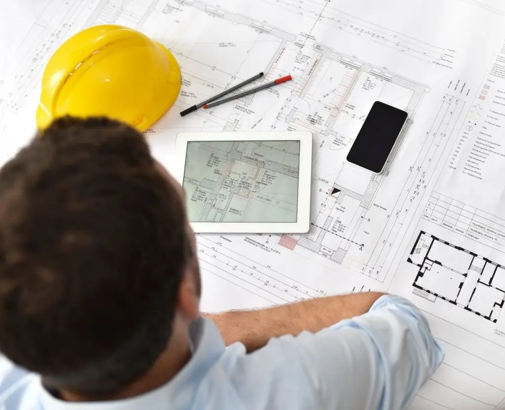 Smart Home im Neubau: Planung mit Bauplan und Tablet auf der Baustelle