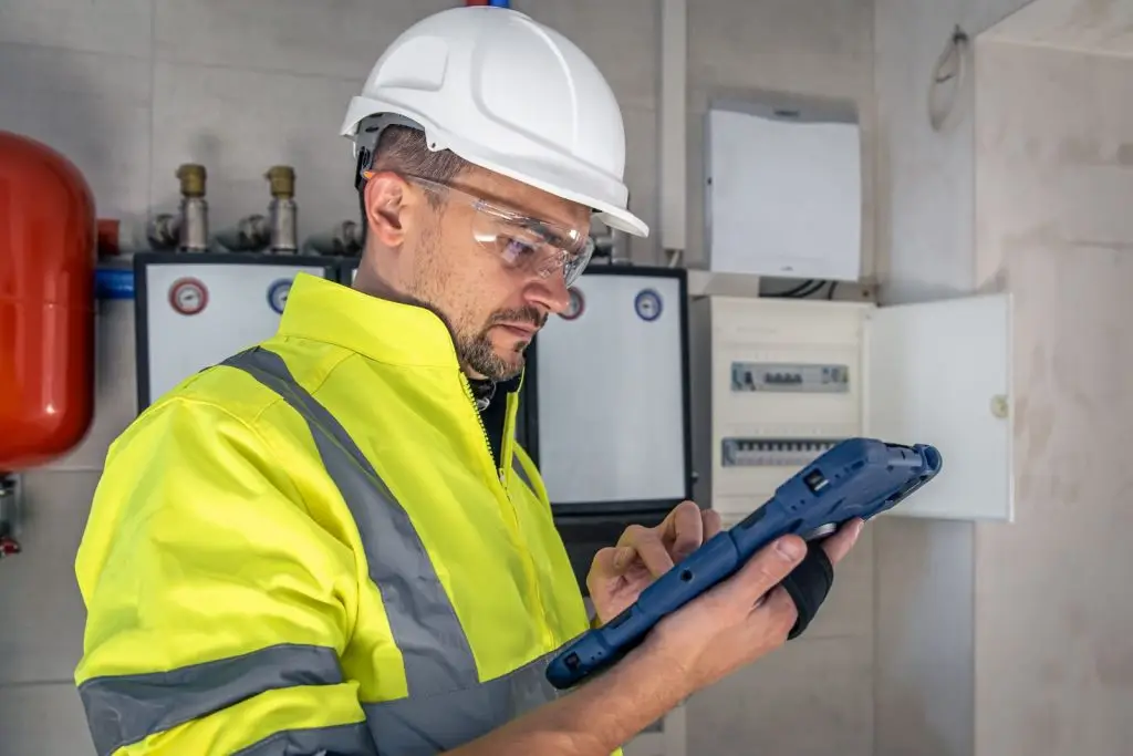 Techniker prüft mit Tablet den Verteiler einer Industrieanlage