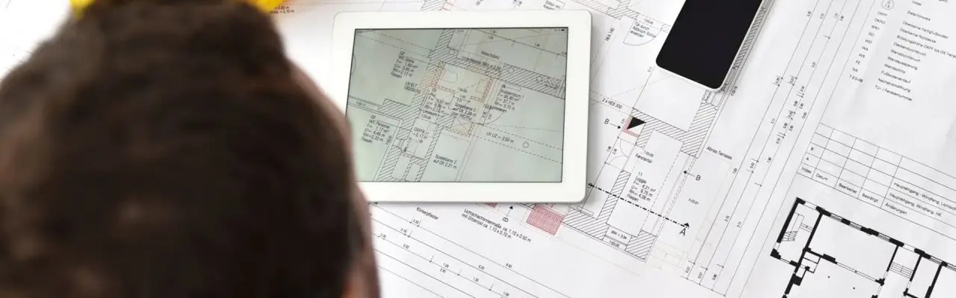 Smart Home im Neubau: Planung mit Bauplan und Tablet auf der Baustelle